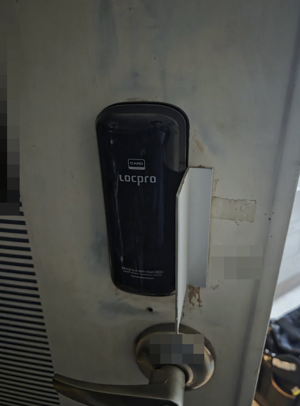 소사구 범박동 출장 — 얼룩진 흰 문에 단 검은 카드 표시 도어락과 옆에 붙은 흰 금속 판, 아래 레버 손잡이